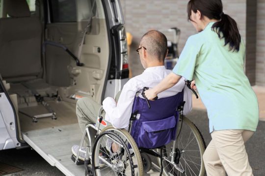 Careworker helping client into transport
