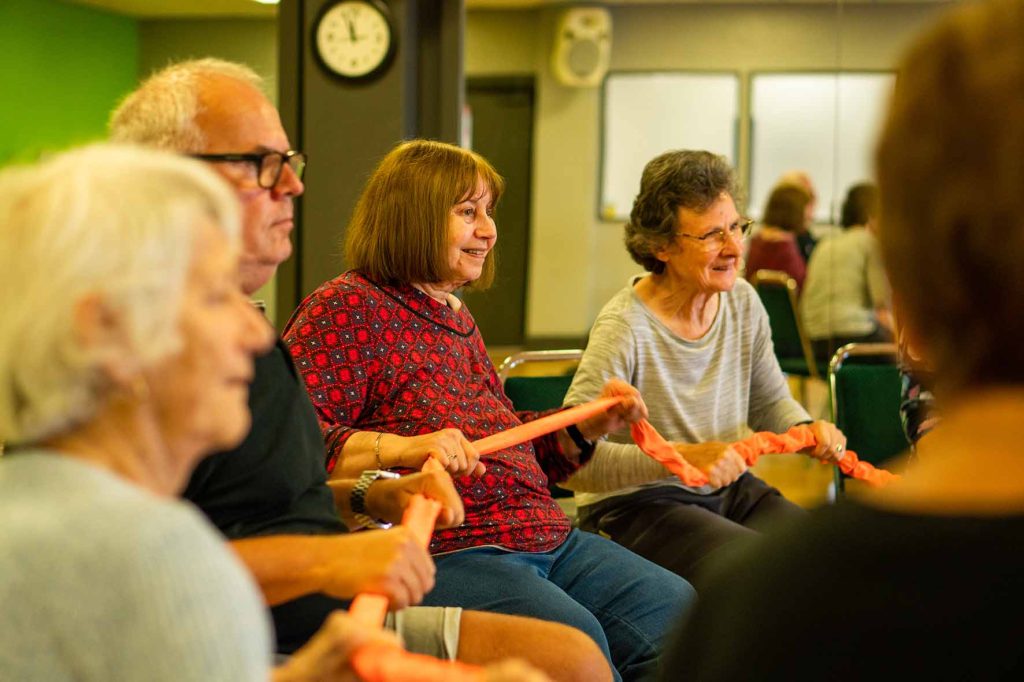 Persons at residential home participating in activity with resistance band