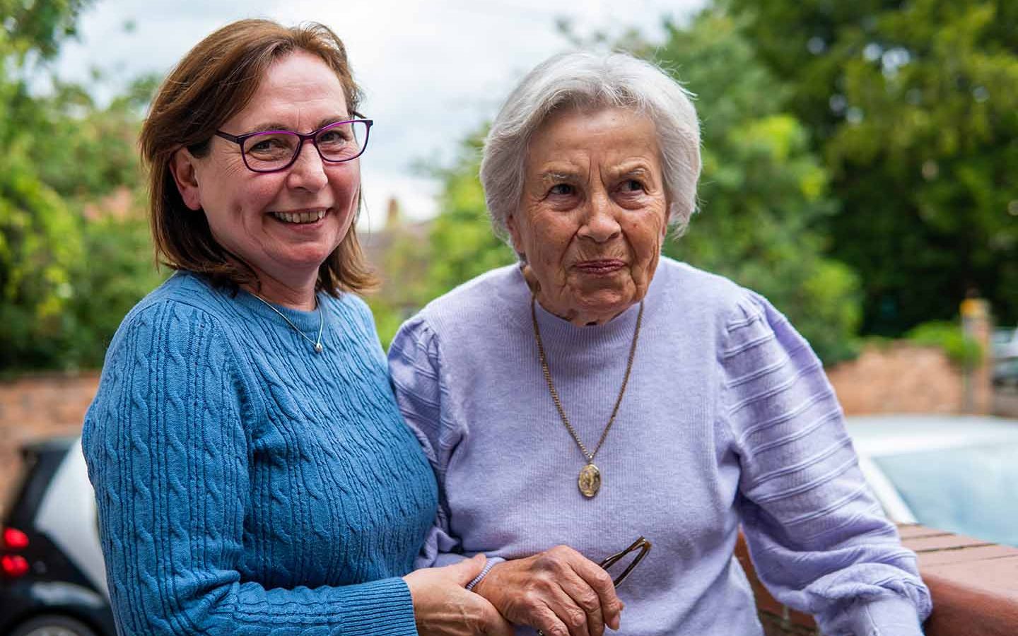 smiling middle aged person helping older person to stand upright