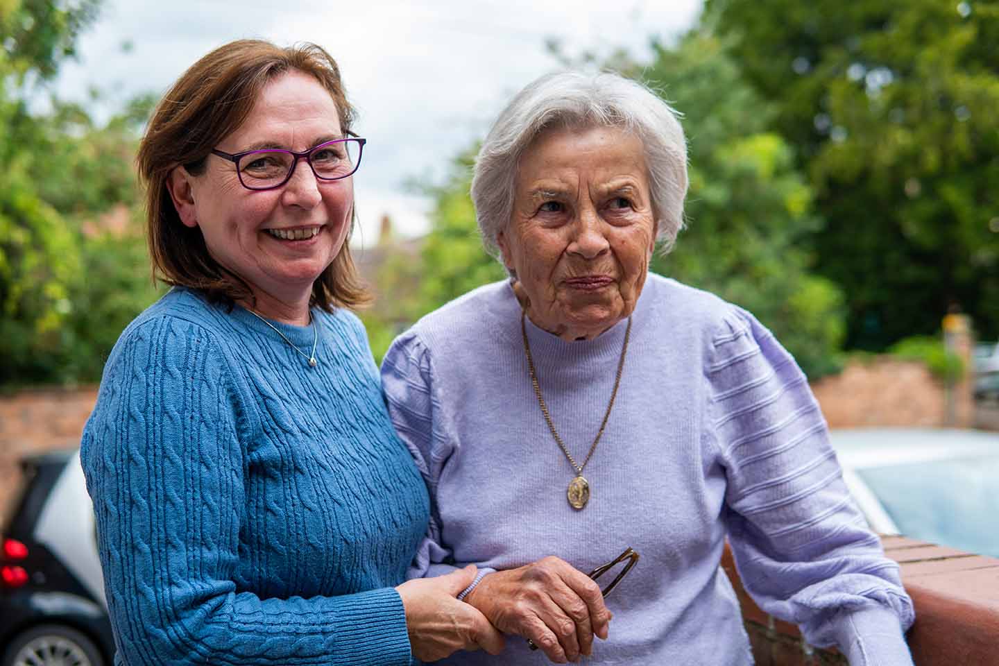 smiling middle aged person helping older person to stand upright