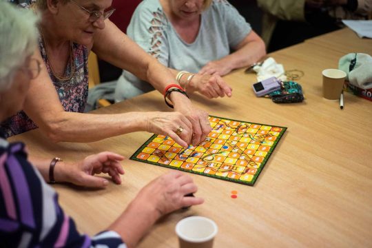 three People playing board game in care environment.