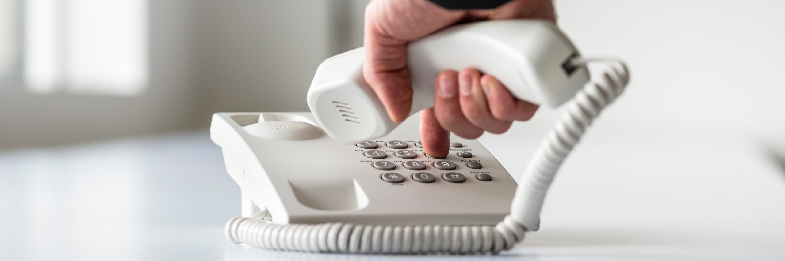 finger pressing button on telephone landline